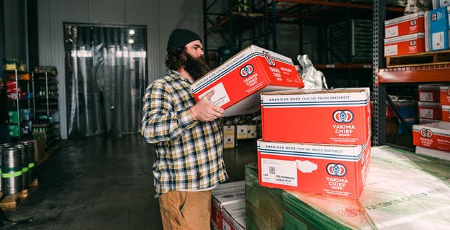 Employé d'entrepôt empilant des boîtes Yakima Chief Hops sur des palettes