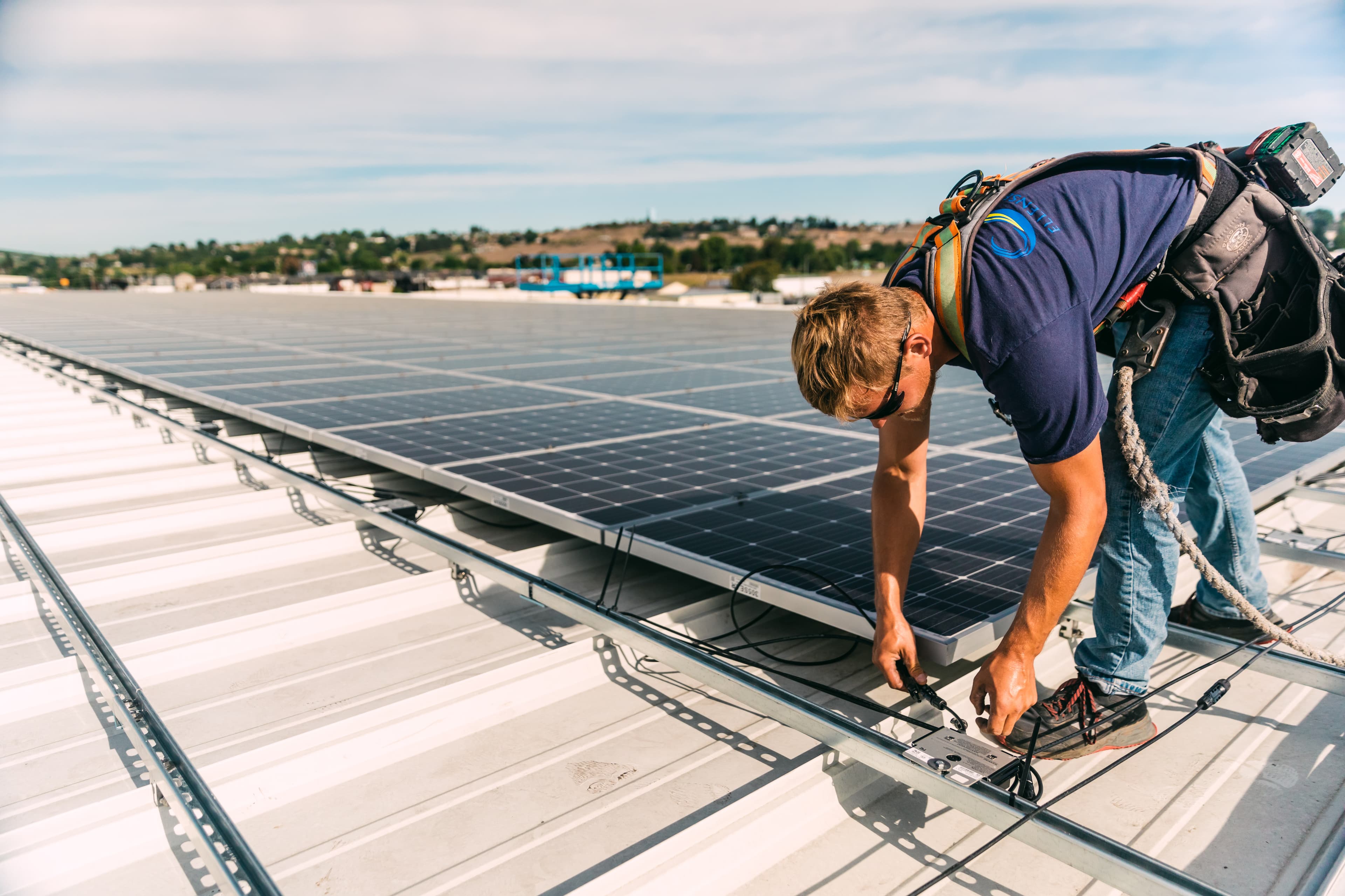 Un homme installe un panneau solaire sur le toit d’un bâtiment.