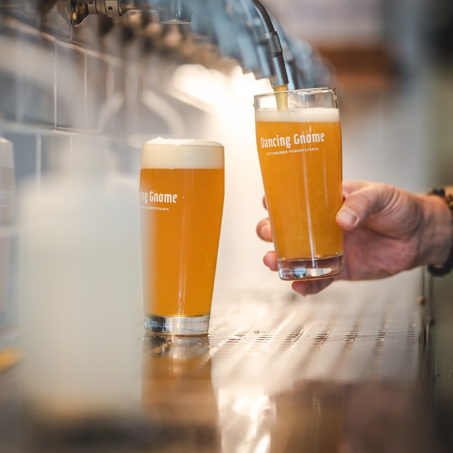 Beer poured into glass cup with 'Dancing Gnome' written on the glass