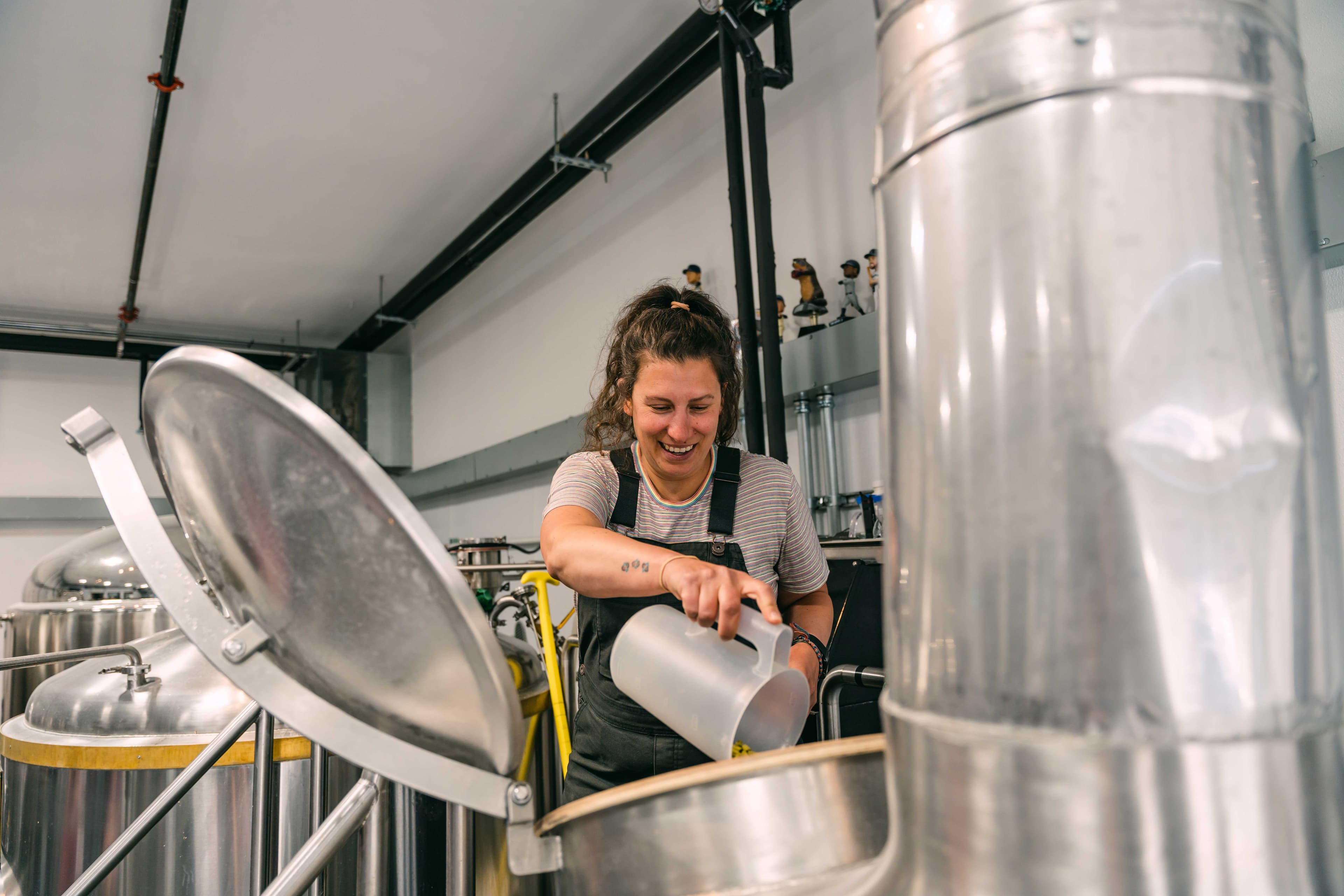 woman pouring a substance into a big silver cylinder