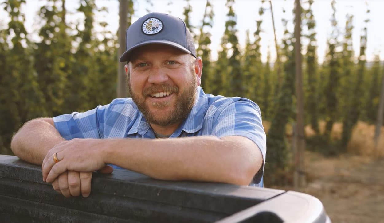 Le cultivateur se tient devant un champ de houblon frais
