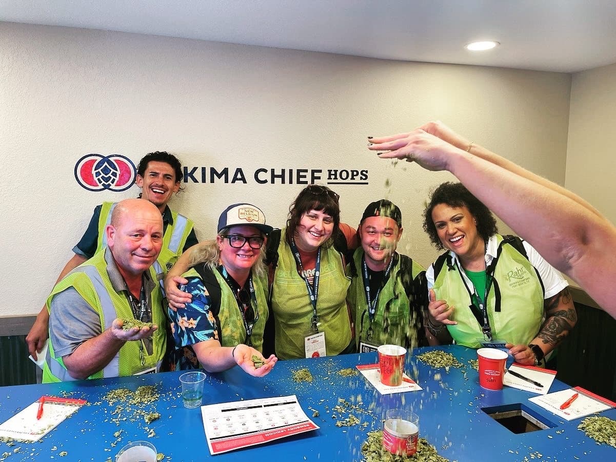 Group of brewers sit around a table of fresh hops